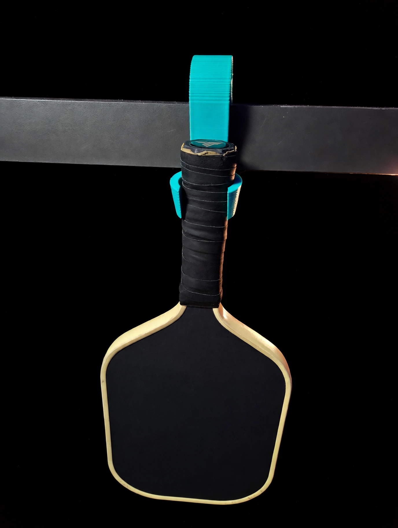 Pickleball Hooked hook holding a paddle on a court fence